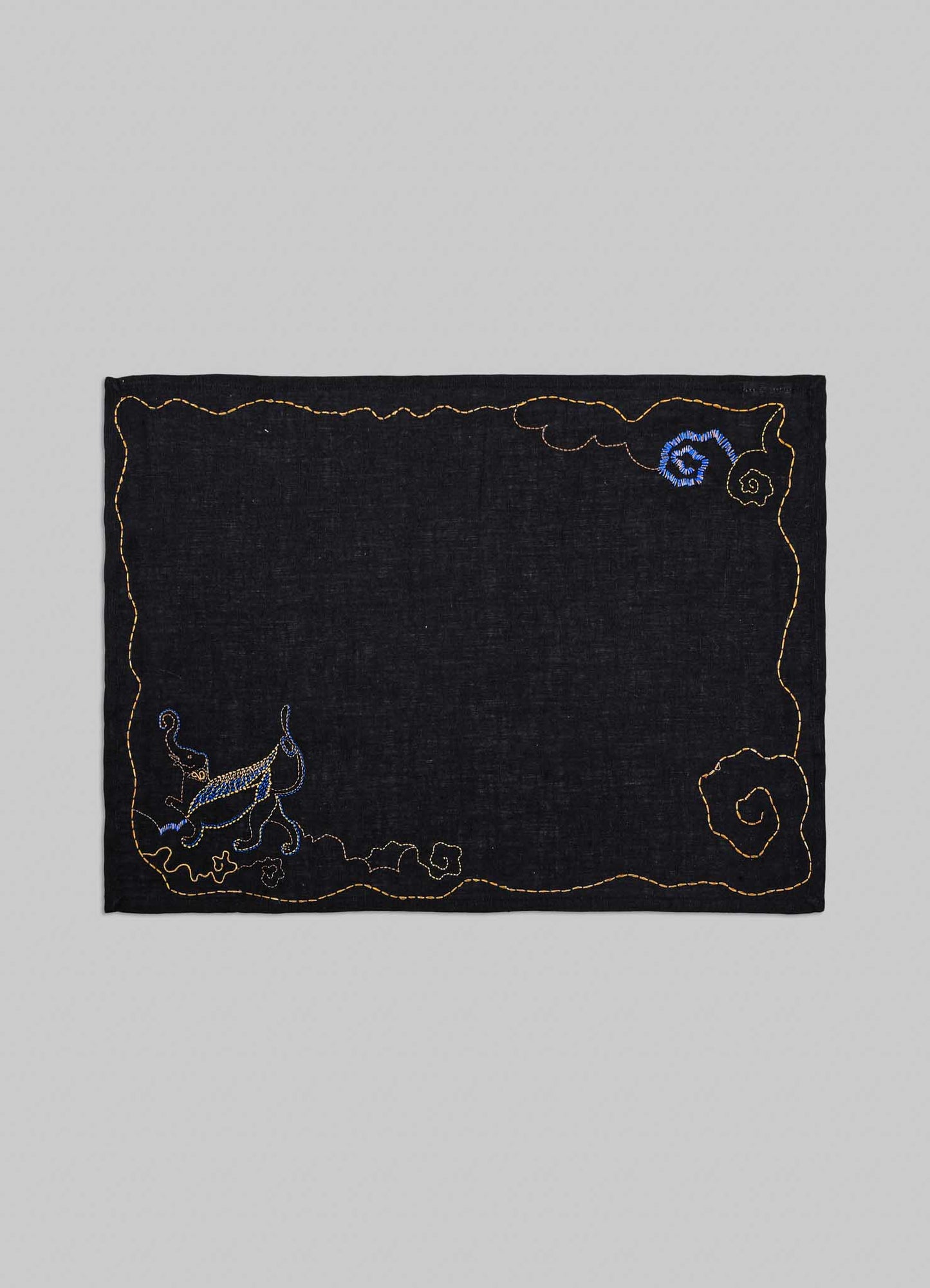 Embroidered black fabric patch with decorative elements on a gray background viya placemats