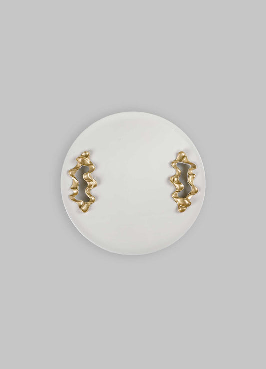 Ceramic wall plate with beige matte finish, featuring two abstract, irregularly shaped metallic gold handles with a wavy design, set against a light gray background.