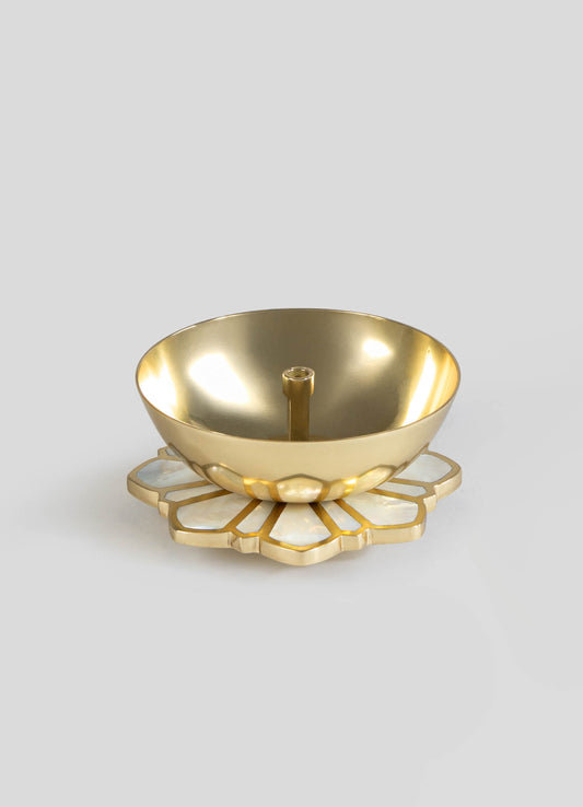A metallic gold candle holder with a smooth, rounded bowl and a central wick, mounted on a decorative base with a floral motif in matching gold and white, made of ceramic or similar material.