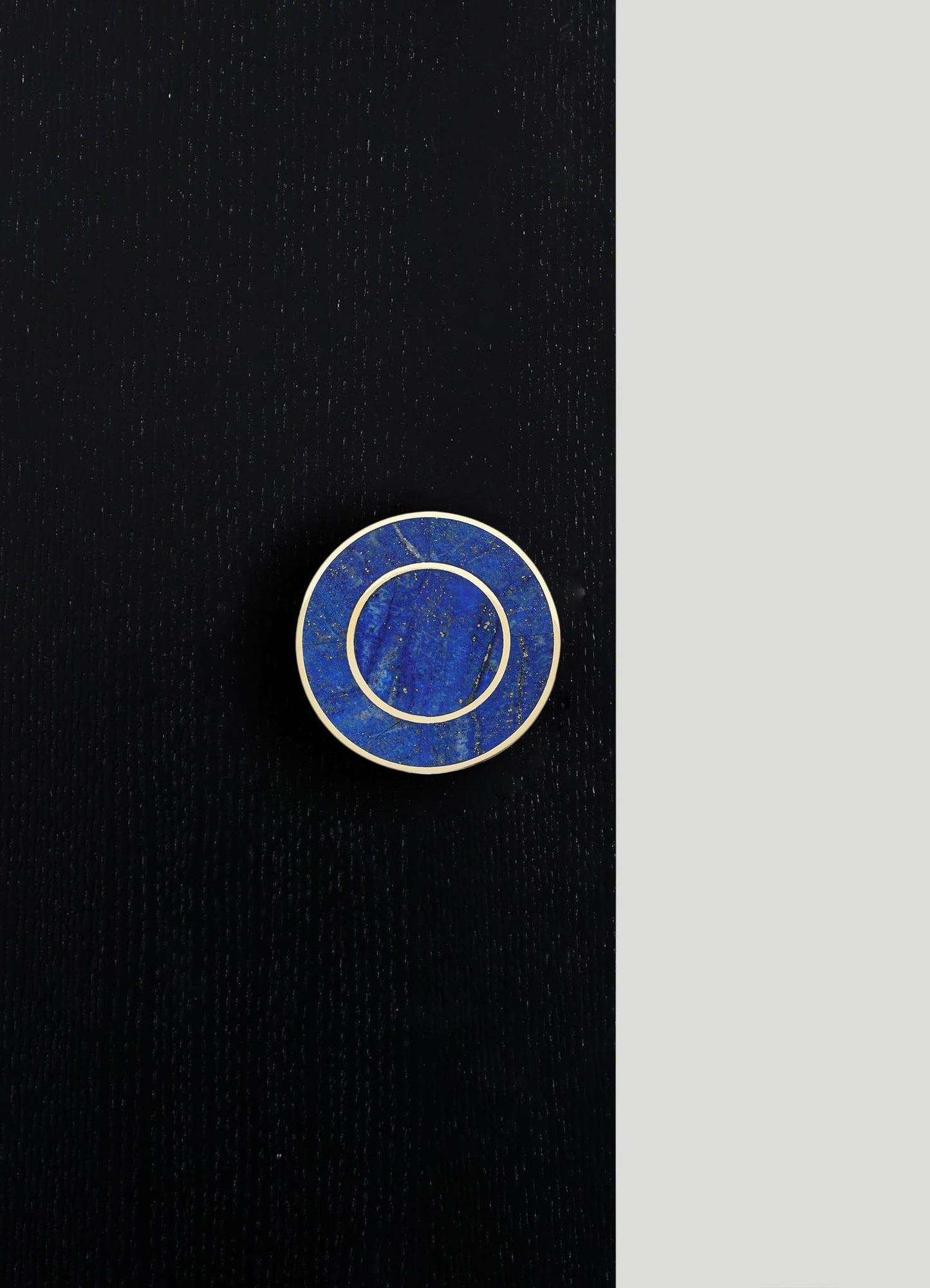 A round jewelry or accessory dish with a blue marble-like pattern and gold-colored borders, placed on a black wooden surface. The design appears contemporary and elegant, emphasizing bold color contrast and metallic accents.