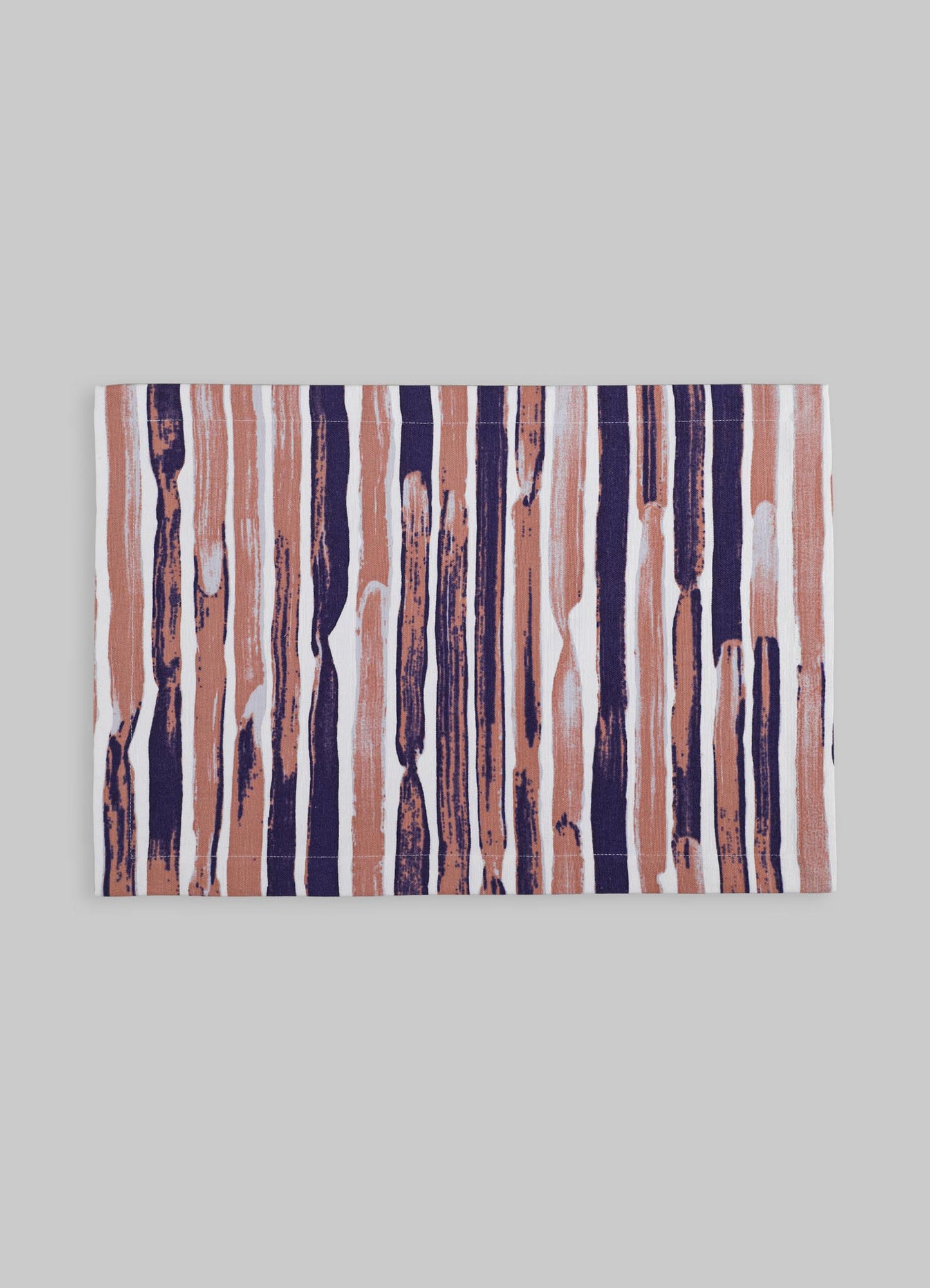 Fabric table runner with a bold, abstract stripe pattern in shades of navy blue, blush pink, and white, showcased on a light gray surface.