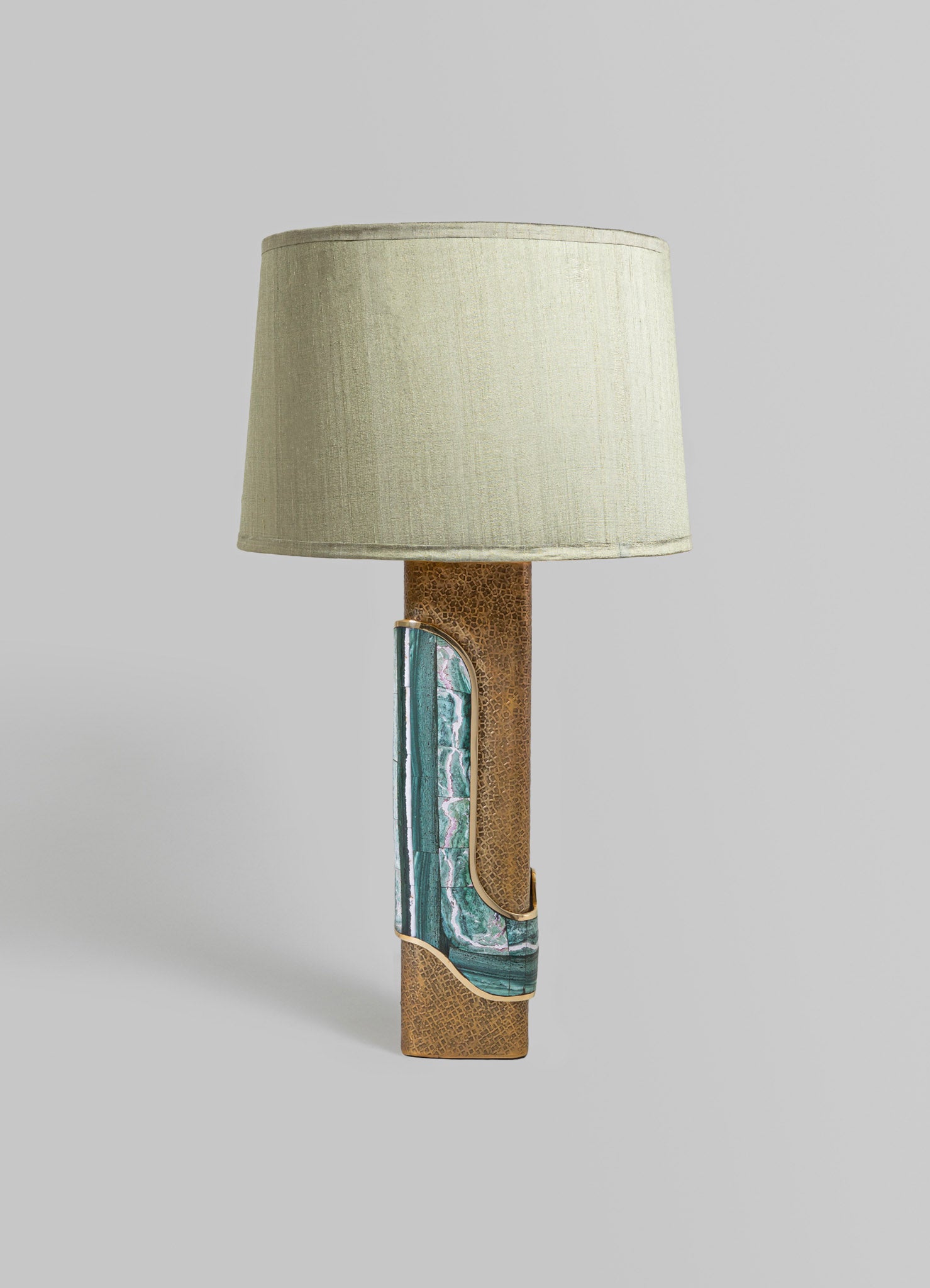 A table lamp with a beige fabric shade and a textured brown ceramic base featuring diagonal inlays of green and blue marbled pattern with gold accents, in a modern style.