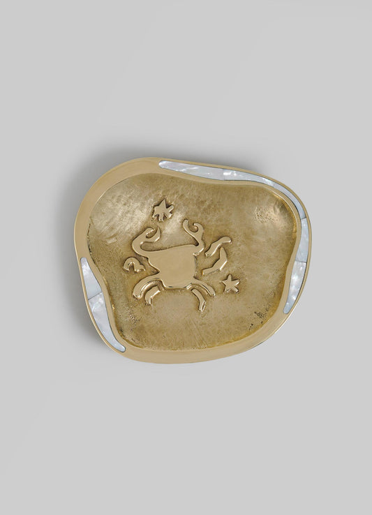 Decorative metal dish with a gold finish, featuring an embossed zodiac sign of Cancer with star and leaf motifs, surrounded by a shell-shaped frame with iridescent inlay accents.