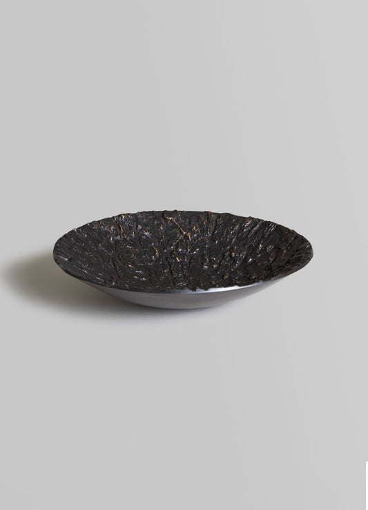 Decorative bowl with textured black interior and smooth white exterior, made of ceramic or similar material, presented on a plain surface.