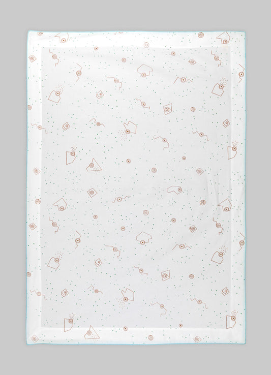 A transparent tablecloth with a printed pattern of orange geometric shapes, small green dots, and abstract motifs, laid flat on a gray surface.