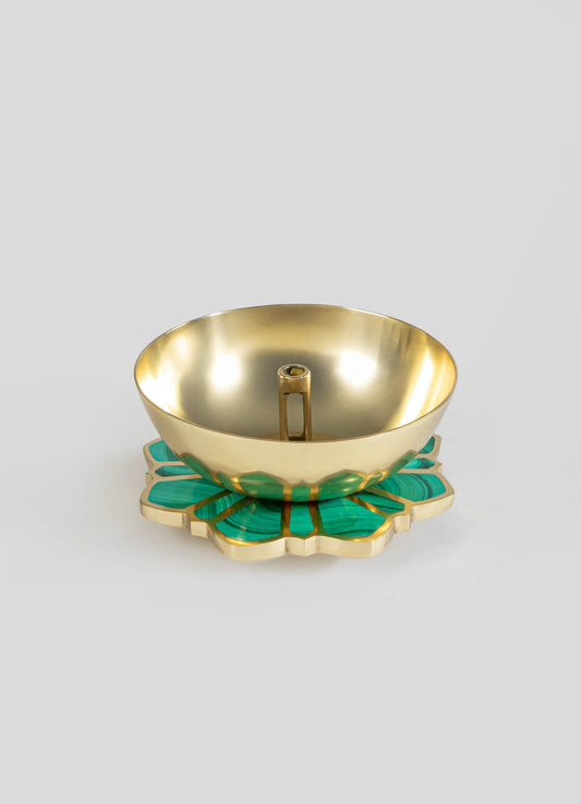 A decorative gold bowl with a smooth, polished interior and a small central handle, resting on an ornate base with turquoise and gold accents. The base features a petal-like shape with a layered, textured design.