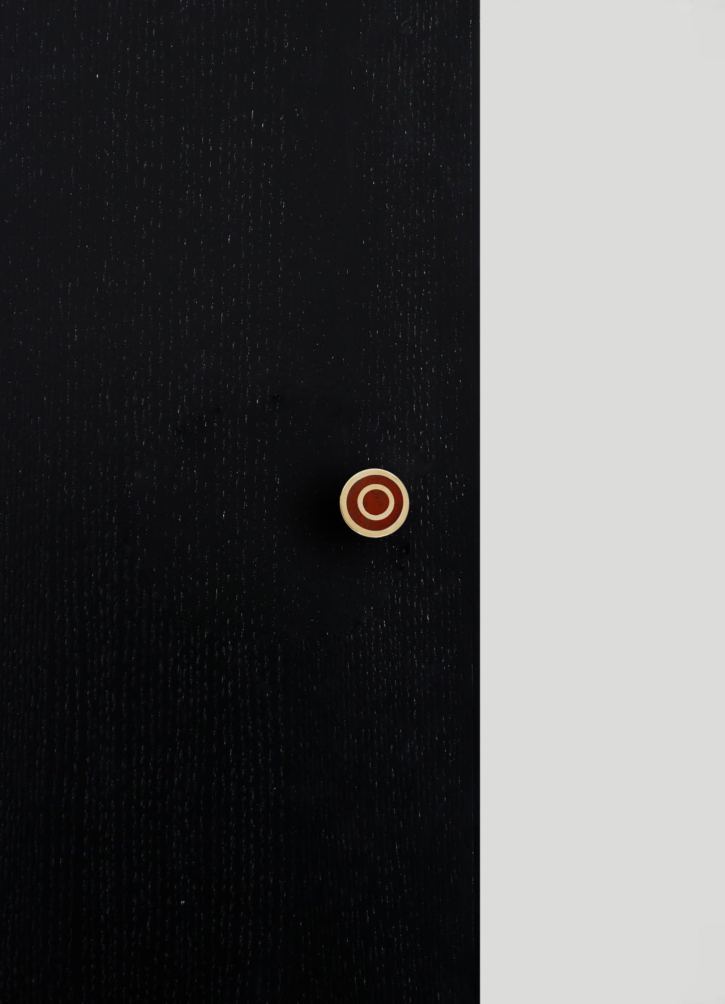 Close-up image of a black fabric with a subtle, dotted pattern and a round button with a metallic rim and a brown center. The fabric appears to be textured, possibly a garment or upholstery material.
