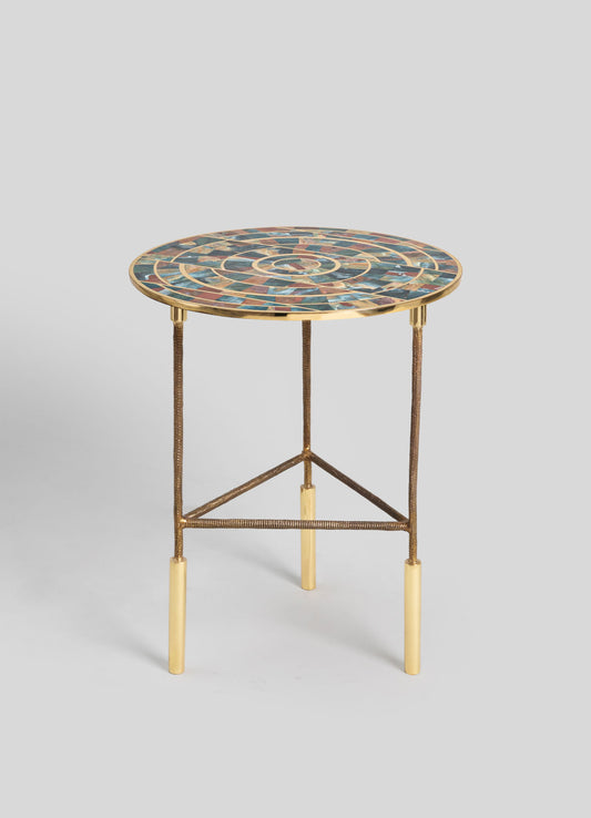 A round side table with a mosaic top featuring multicolored stone tiles arranged in a spiral pattern. The table has a metal base with a gold finish, slender legs, and a triangular support structure.
