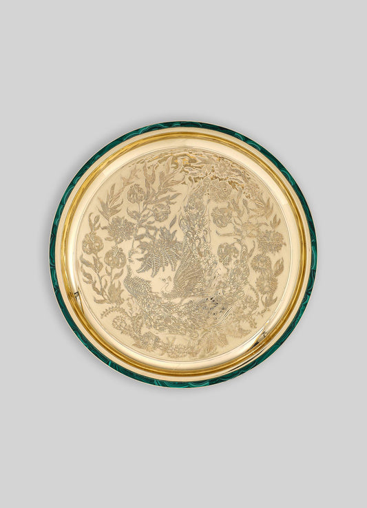 A decorative round tray with a gold-toned interior featuring intricate engraved motifs of peacocks and floral patterns, bordered by a green rim with a swirling pattern.