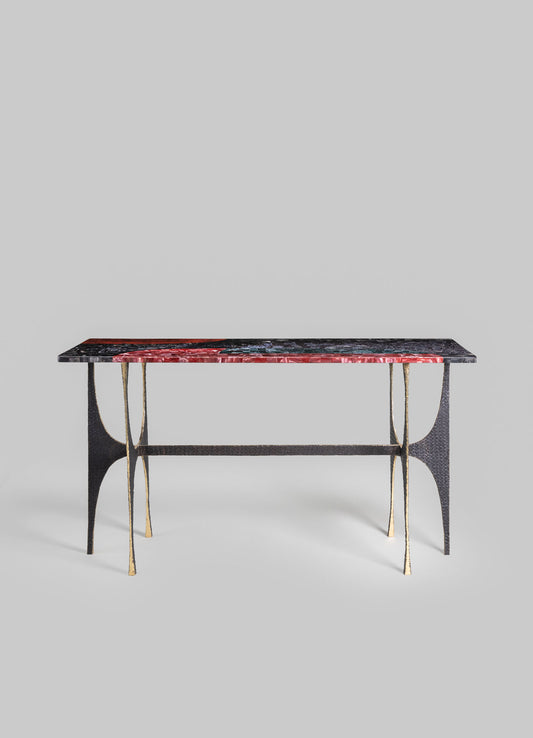 A rectangular table with a marble top featuring red, black, and green veining, supported by black and gold metal legs with curved details, in a contemporary style.