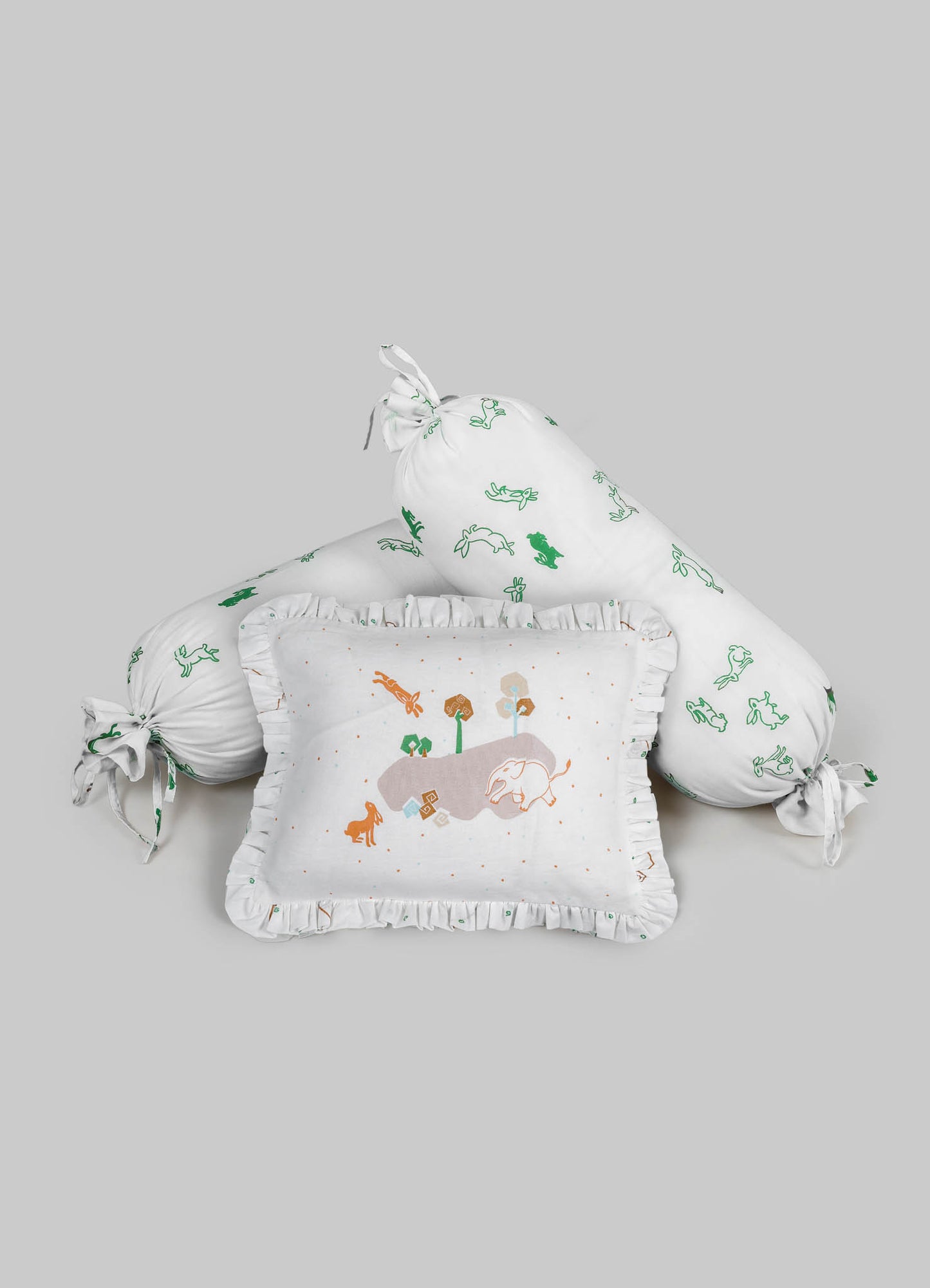 Decorative baby bedding set featuring a cylindrical pillow and a square pillow with ruffled edges, made of soft white fabric with embroidered animal and nature motifs in green, orange, and brown. The set includes a tied bolster with matching embroidered patterns, designed with a playful and natural theme suitable for nursery decor.