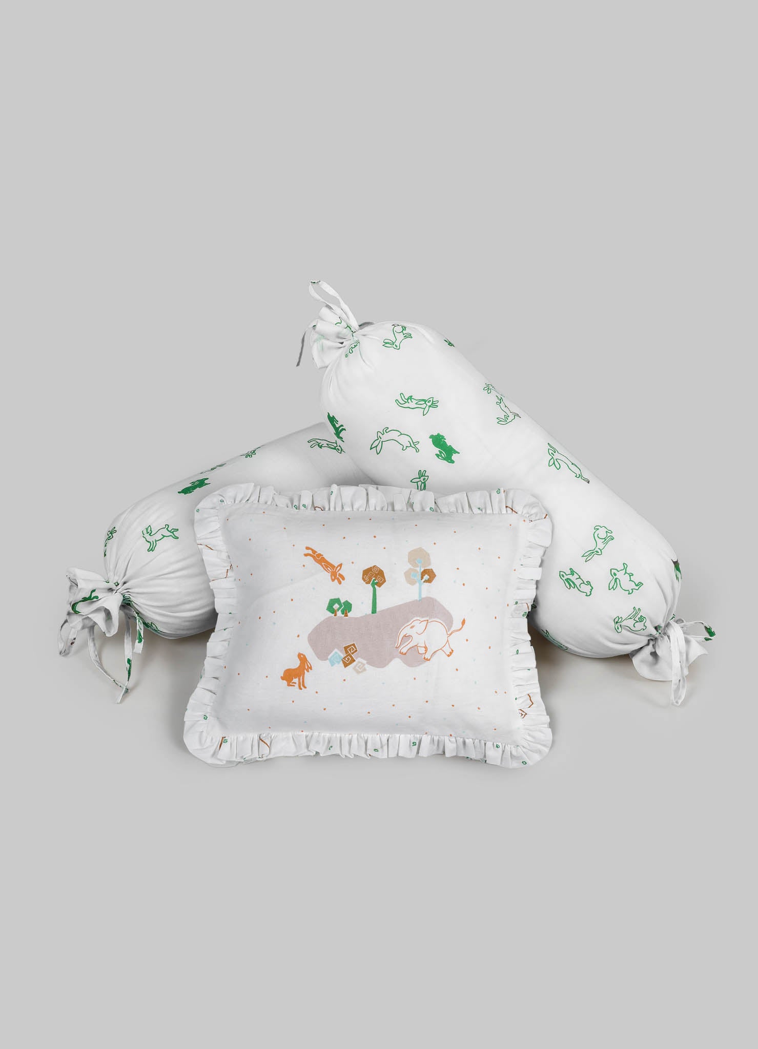Decorative baby bedding set featuring a cylindrical pillow and a square pillow with ruffled edges, made of soft white fabric with embroidered animal and nature motifs in green, orange, and brown. The set includes a tied bolster with matching embroidered patterns, designed with a playful and natural theme suitable for nursery decor.