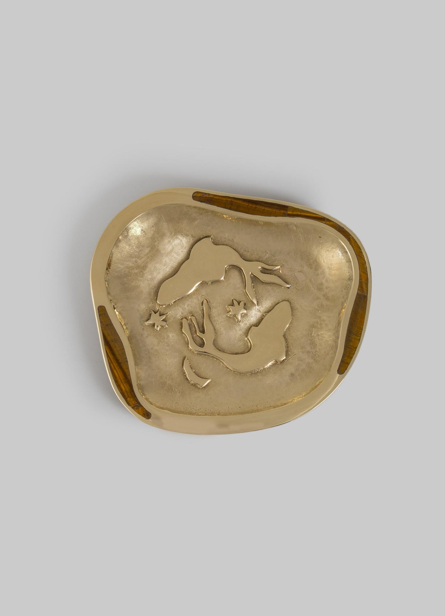 A decorative brass tray with an irregular rounded-square shape, featuring an engraved map motif and a polished gold finish. The tray has inlaid wooden accents along the rim, contributing to a handcrafted and contemporary style.