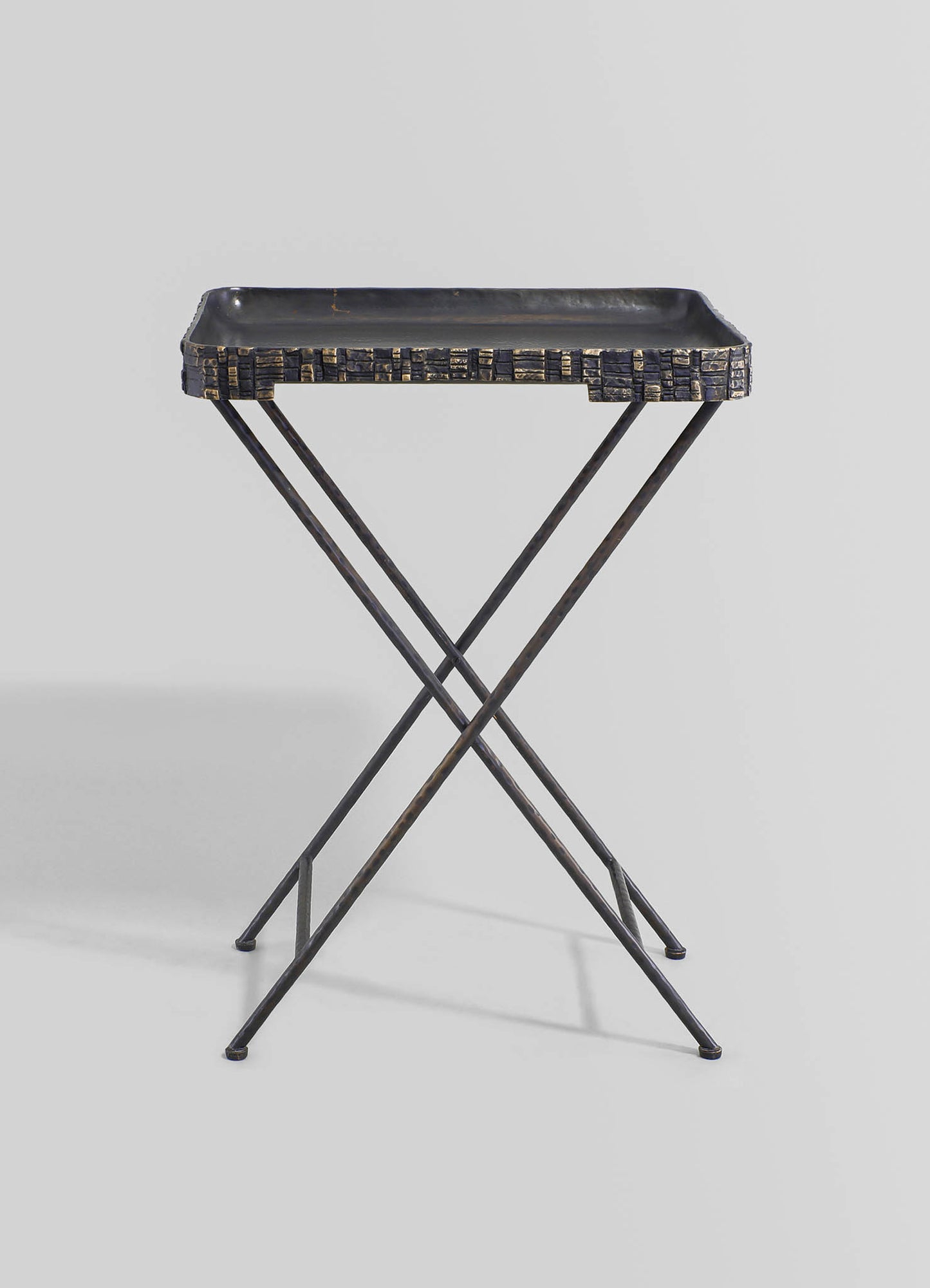 A black metal tray with a textured, geometric pattern on the edge, supported by a slender, intersecting X-shaped metal frame, presented against a plain background.