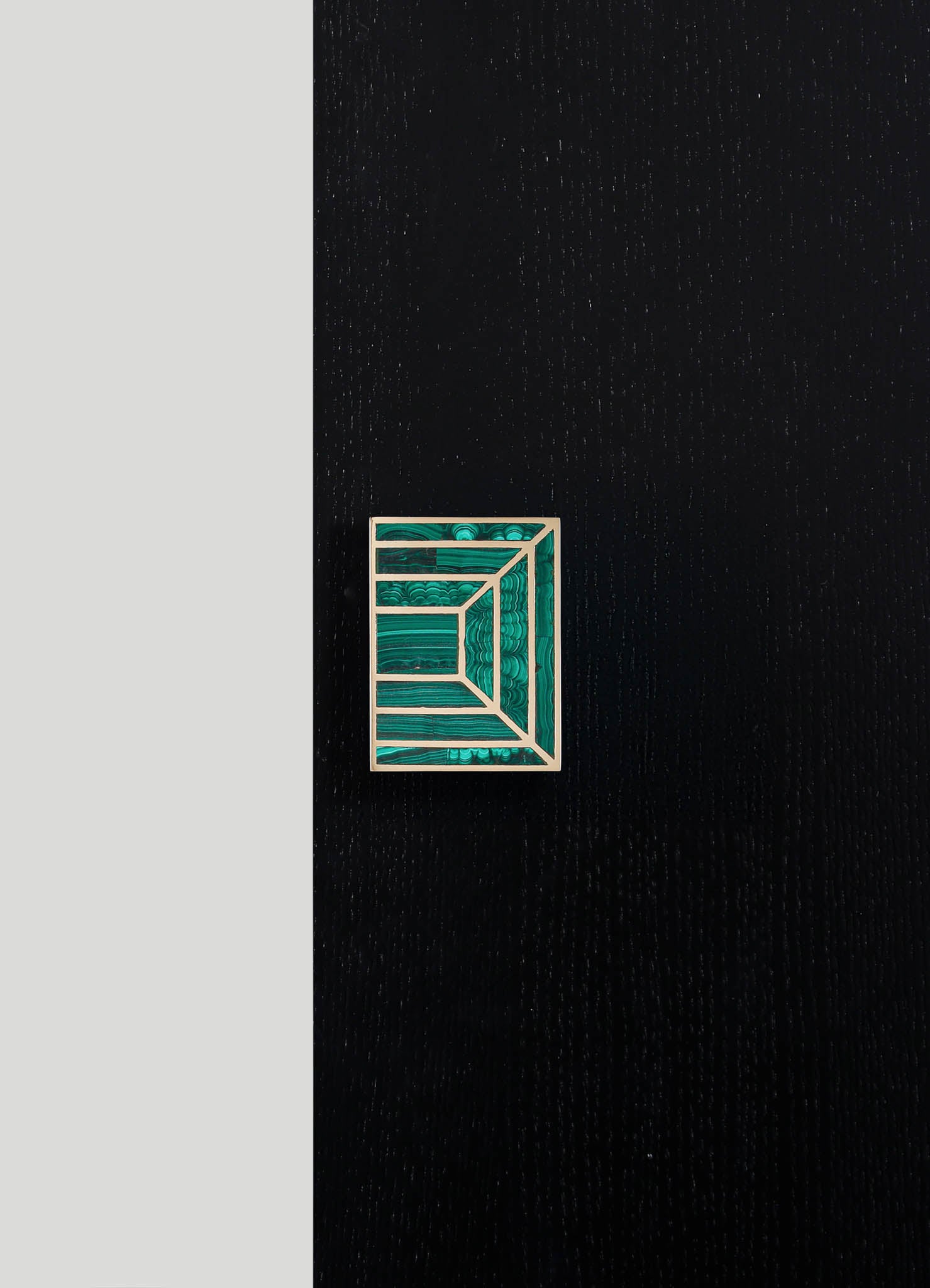 A geometric brooch with a rectangular shape, featuring layered, concentric lines in shades of teal and turquoise, mounted on a black textured surface.