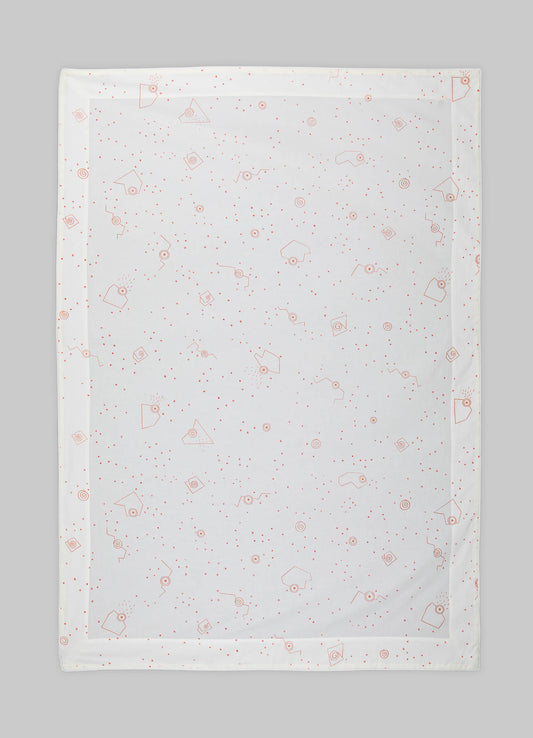 Silk tablecloth with geometric motifs in a soft red tone, featuring small dots and angular shapes, laid across a flat surface.