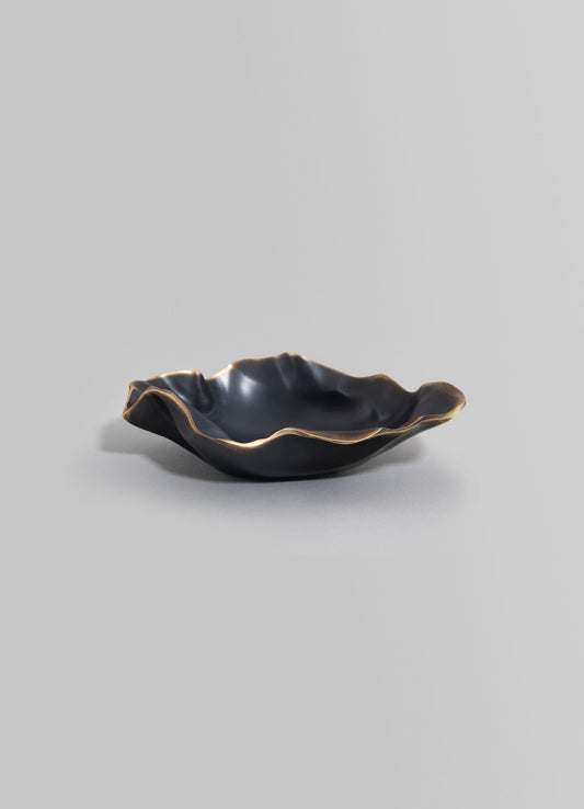 Black ceramic bowl with an irregular, wavy edge and metallic gold accents, featuring a handcrafted design.