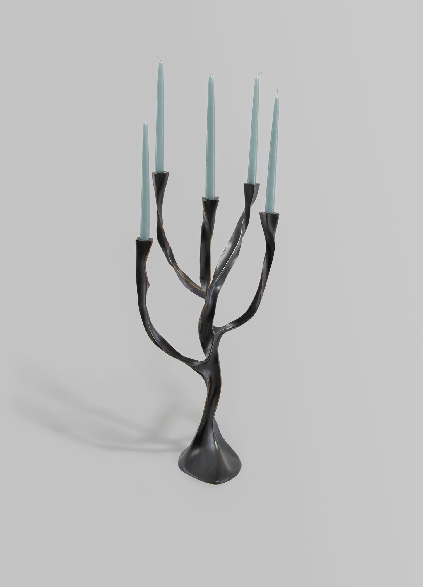 Metallic black and gold candle holder with a twisted, branch-like design, holding seven light blue taper candles.