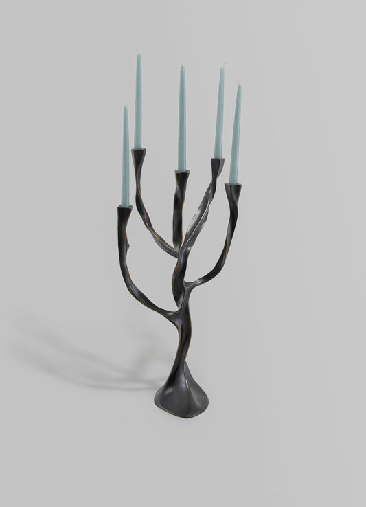 Metallic black and gold candle holder with a twisted, branch-like design, holding seven light blue taper candles.