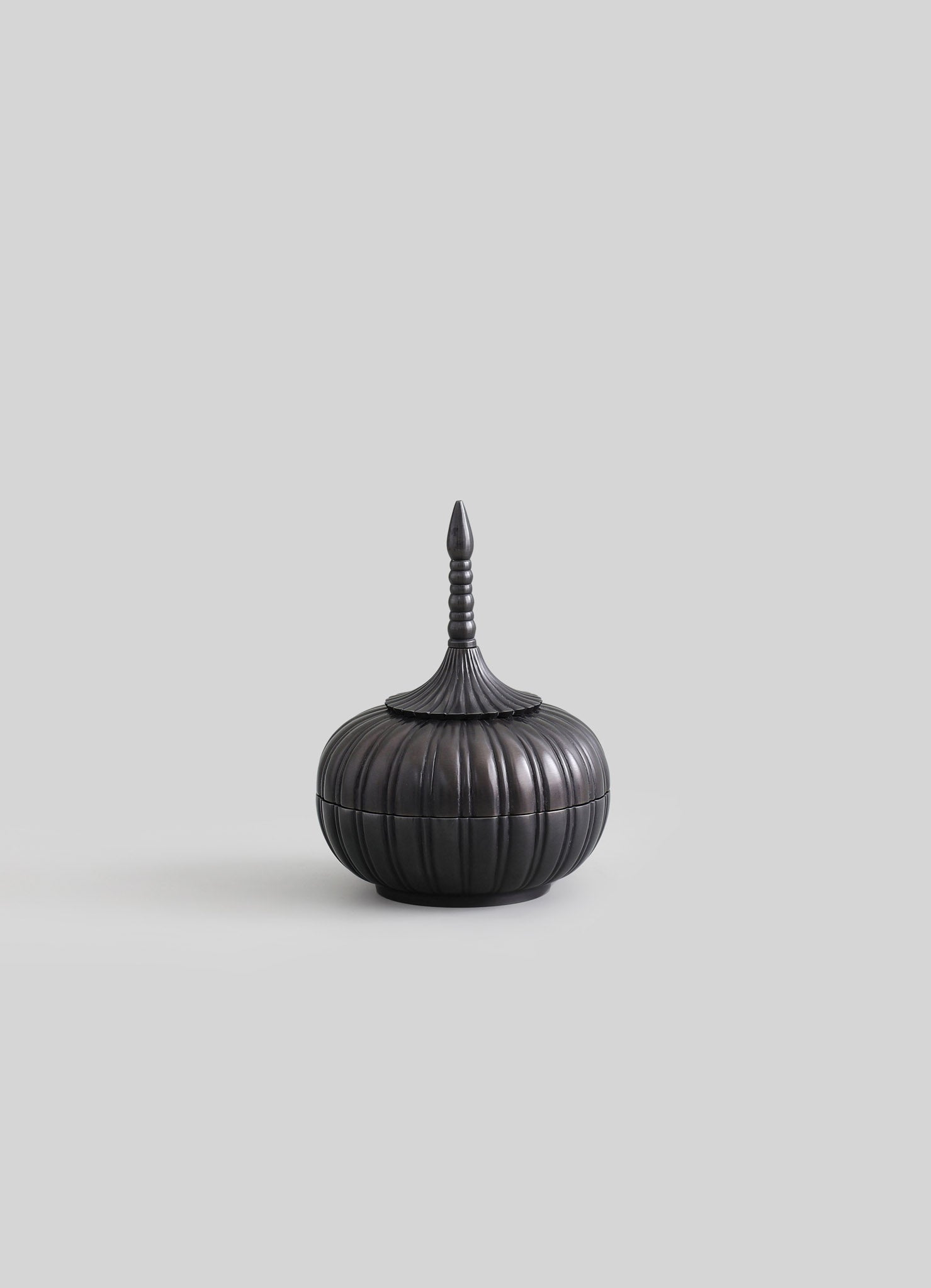 A black, lacquered wooden container with a rounded, ribbed body and a tall, pointed lid featuring stacked rings and a finial, styled in a traditional or handcrafted aesthetic.