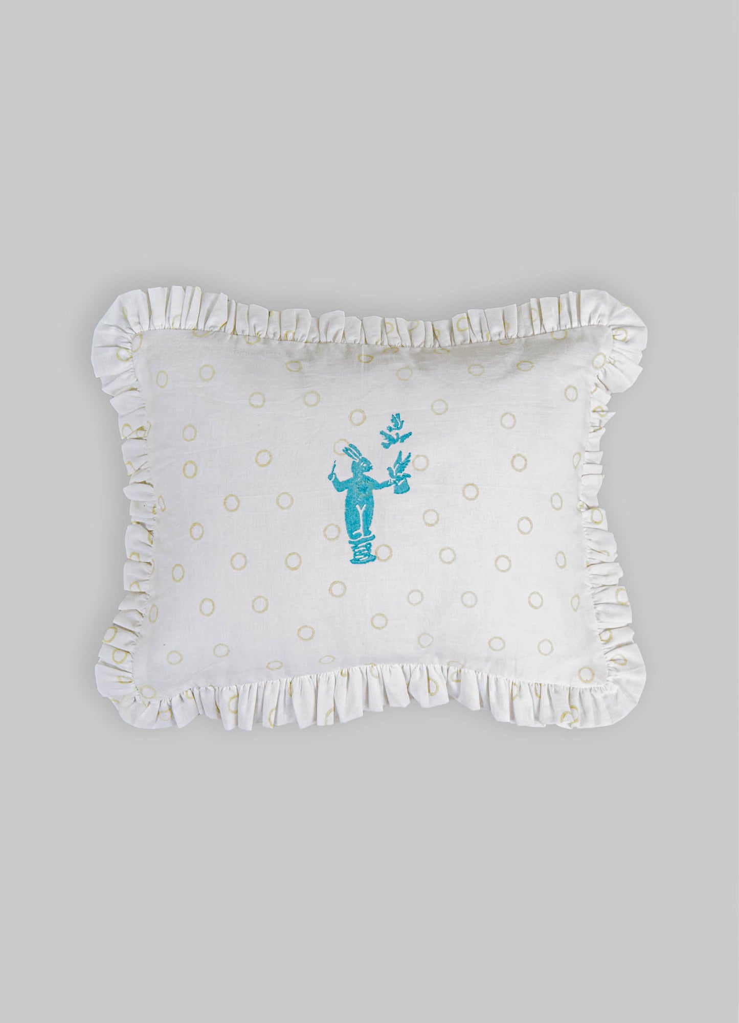 Cotton pillow with a ruffled edge and a playful embroidered blue figure holding a branch, featuring a cream-colored background with small beige circles.