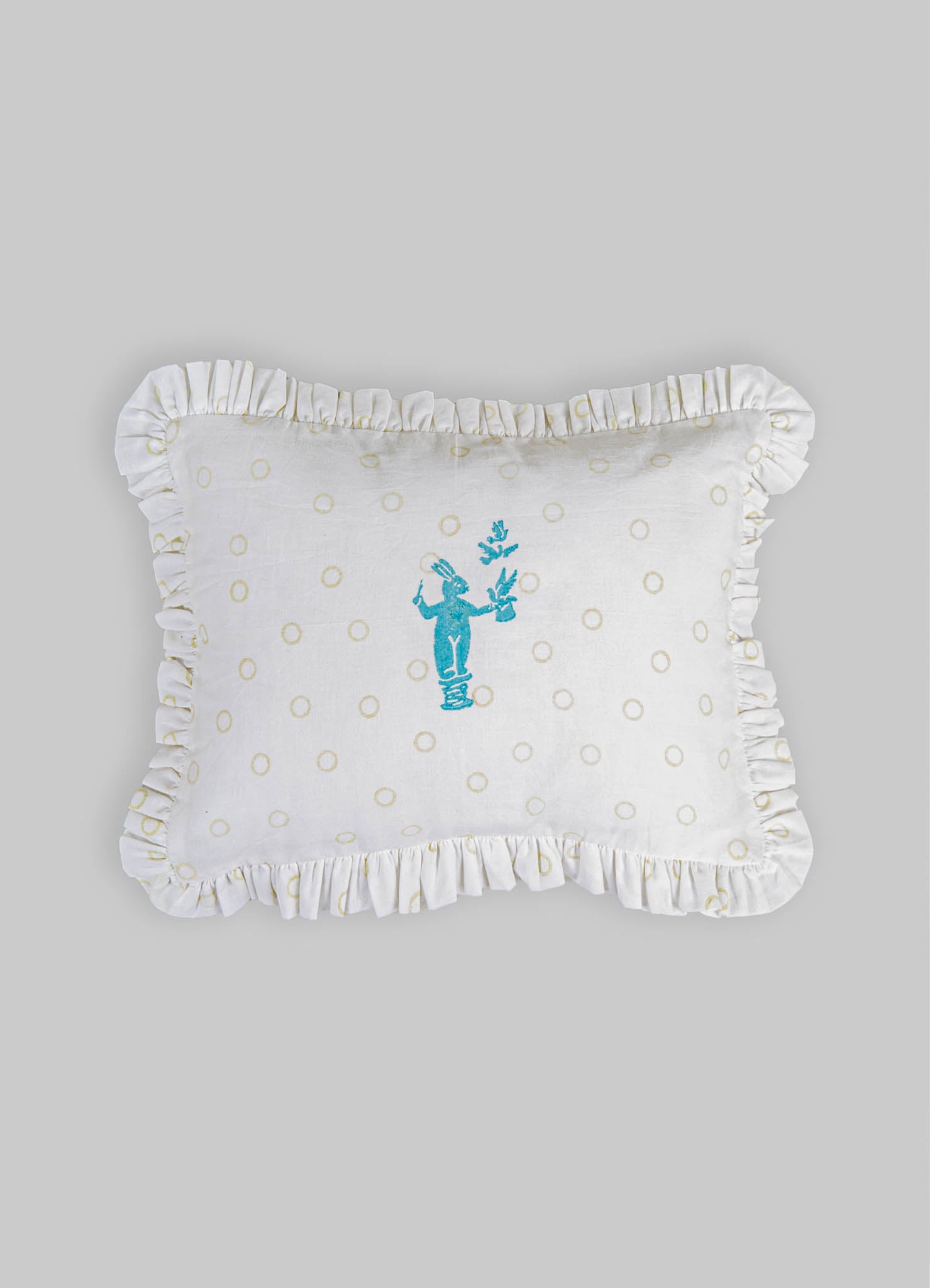 Cotton pillow with a ruffled edge and a playful embroidered blue figure holding a branch, featuring a cream-colored background with small beige circles.