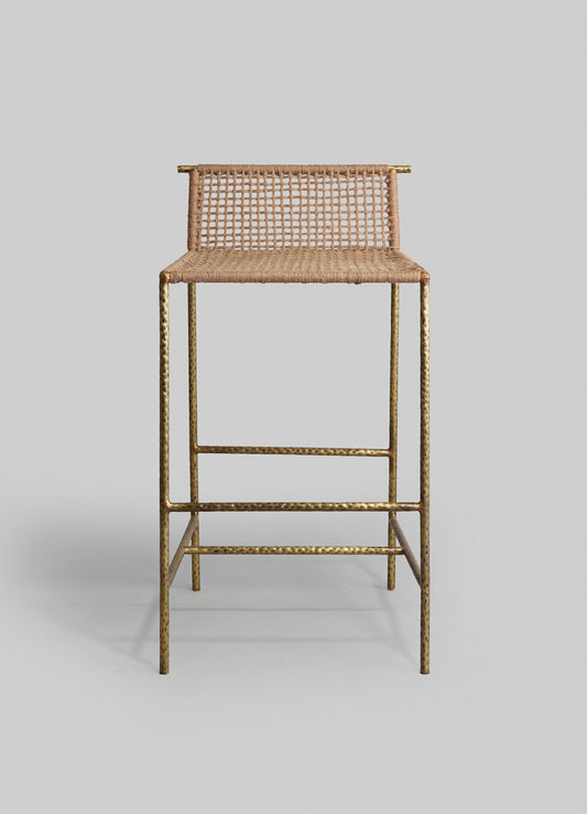A bar stool featuring a woven rattan seat and backrest with a natural finish, supported by a gold-toned hammered metal frame. The design combines rustic craftsmanship with contemporary metallic accents.
