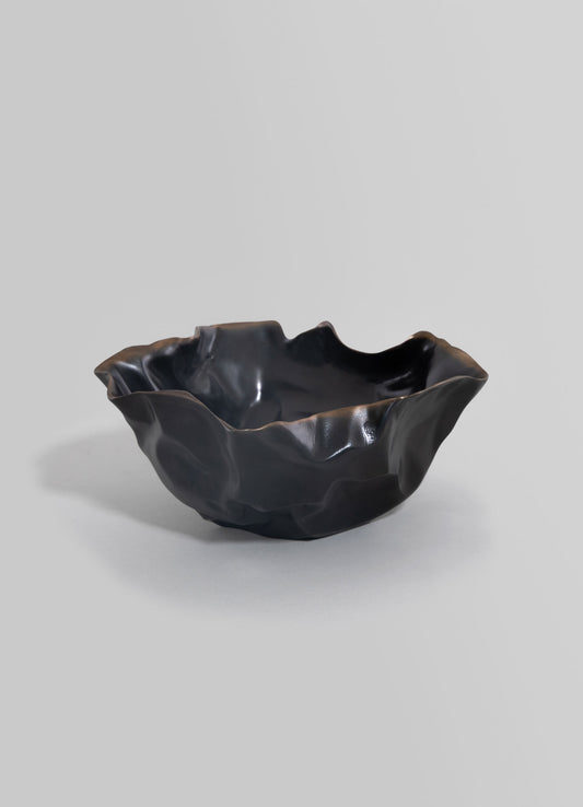 A black ceramic bowl with a crinkled, irregular edge and a glossy finish, featuring a handcrafted, organic shape set against a plain background.