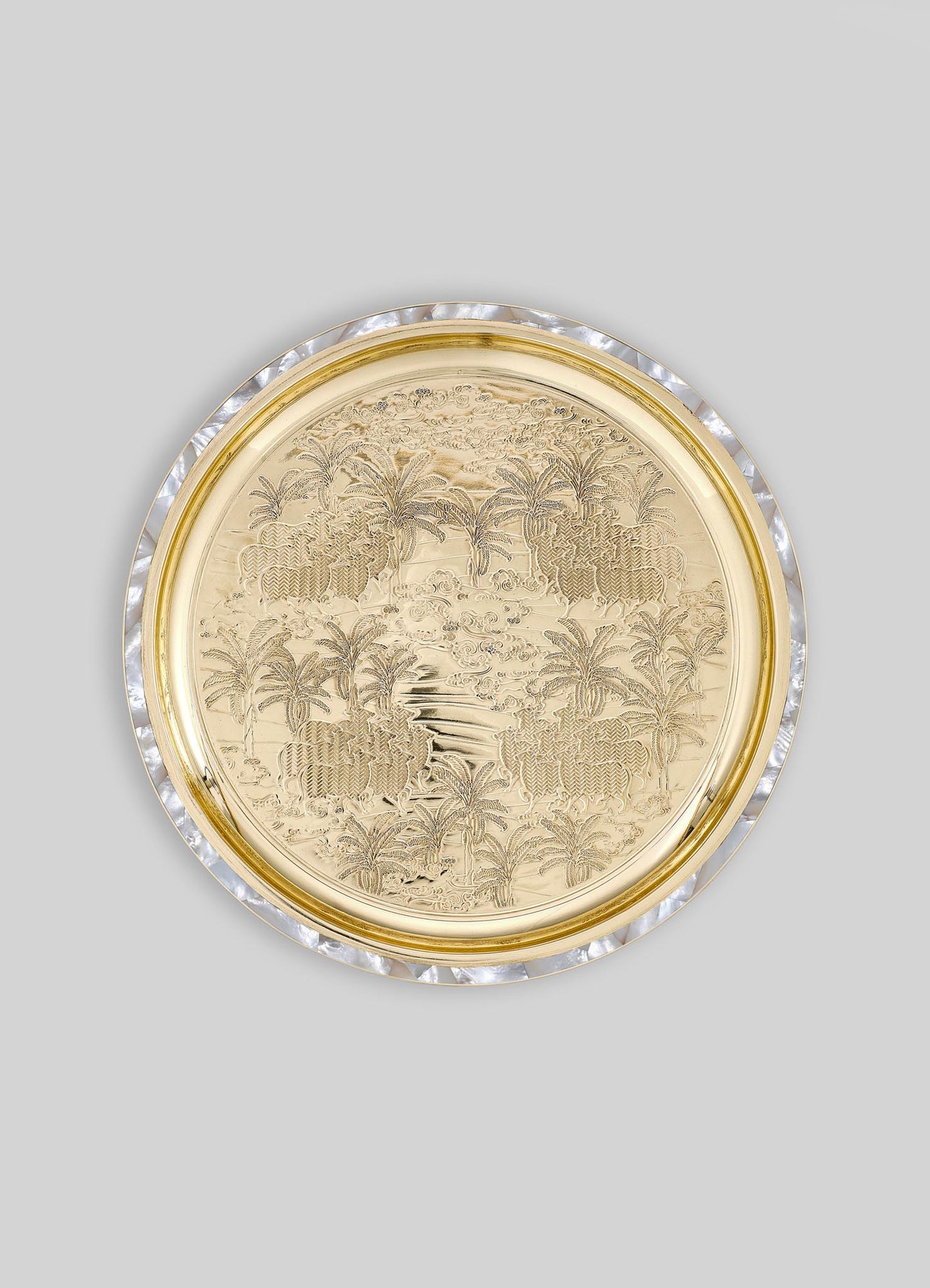 Decorative round tray with intricate engraved landscape and palm tree motifs, crafted from gold-toned metal with a mother-of-pearl and clear shell rim. The tray features a luxurious, handcrafted design with a mix of metallic and iridescent finishes.