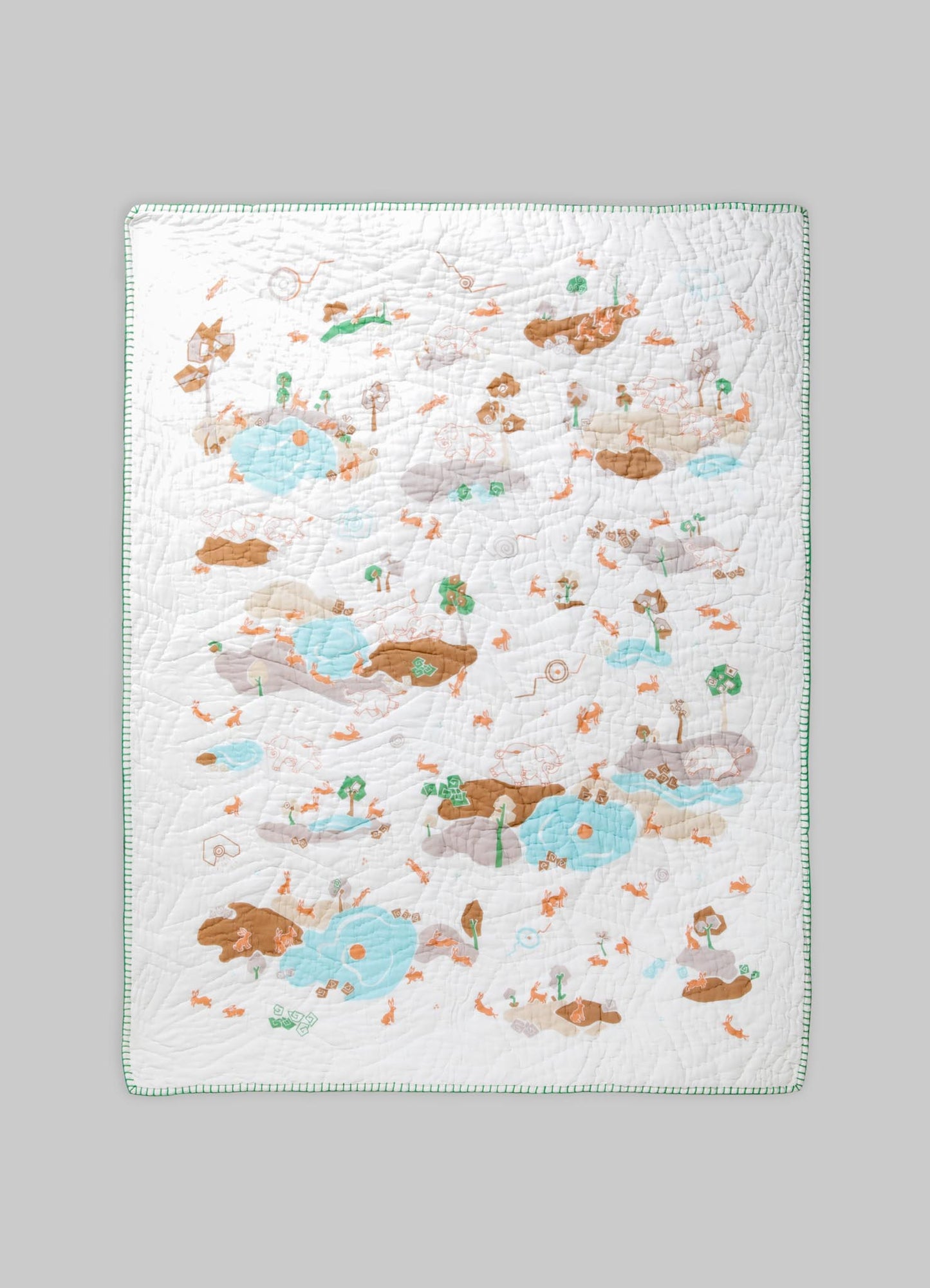 Quilt with a playful, illustrative print featuring animals, trees, and water elements in pastel shades of blue, brown, and green on a white background, bordered with a green stitched edge.