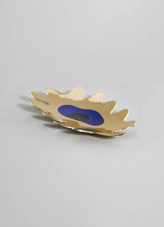 A decorative tray with an organic, leaf-like shape in metallic gold finish, featuring a blue and black marble center detail, placed on a plain light background.