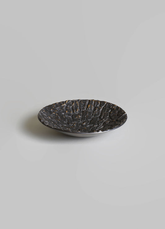 A black textured ceramic bowl with a rough, hammered surface finish.
