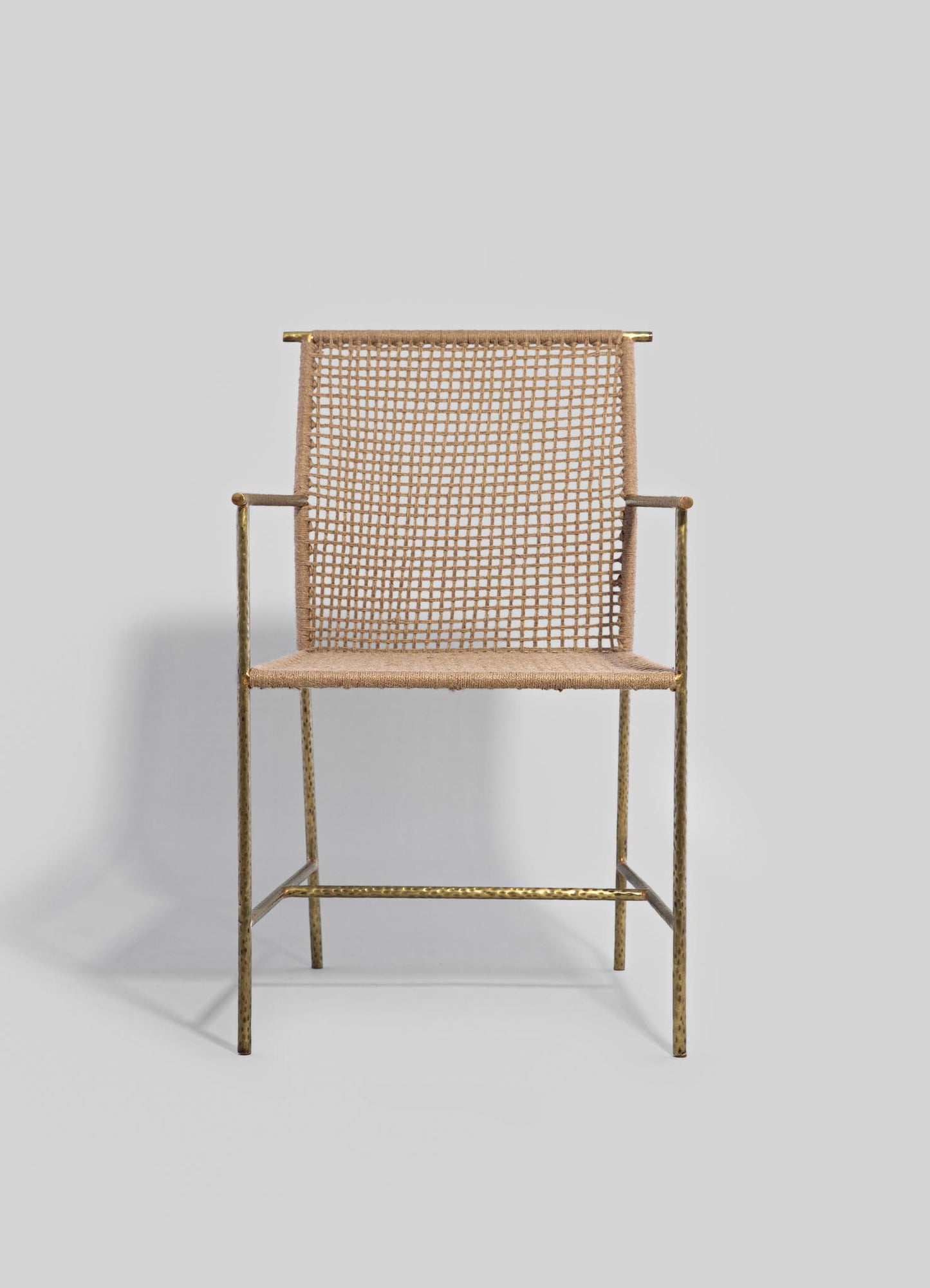 A chair with a gold metal frame and a woven beige rattan backrest and seat, featuring a minimalist and contemporary design.