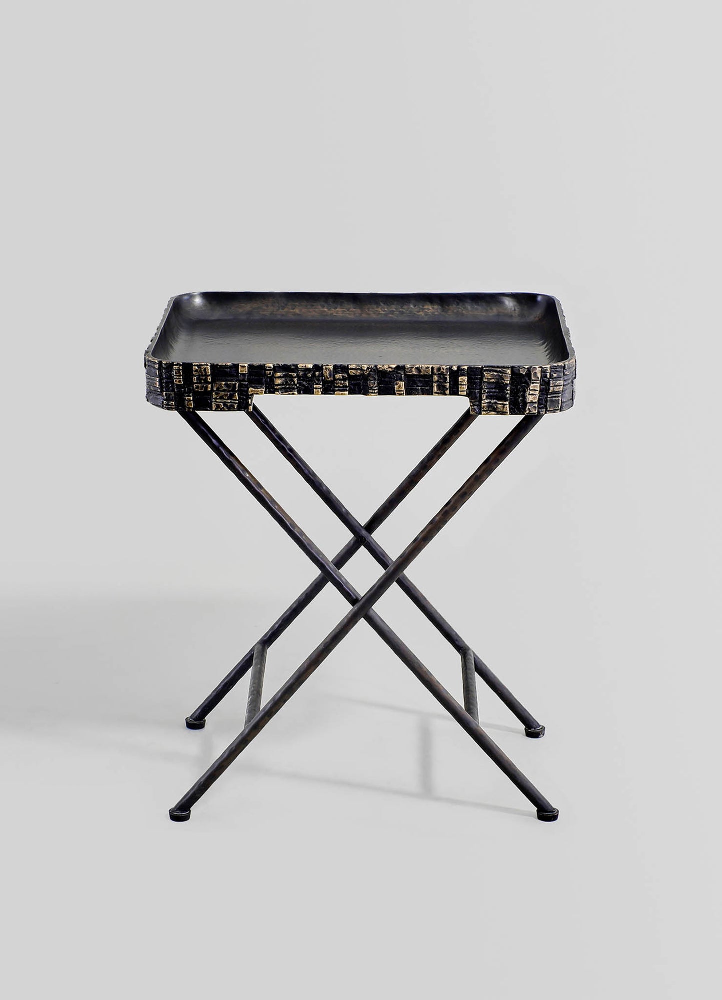 A black metal tray with a textured, carved pattern edge, mounted on a minimalist X-shaped metal stand.