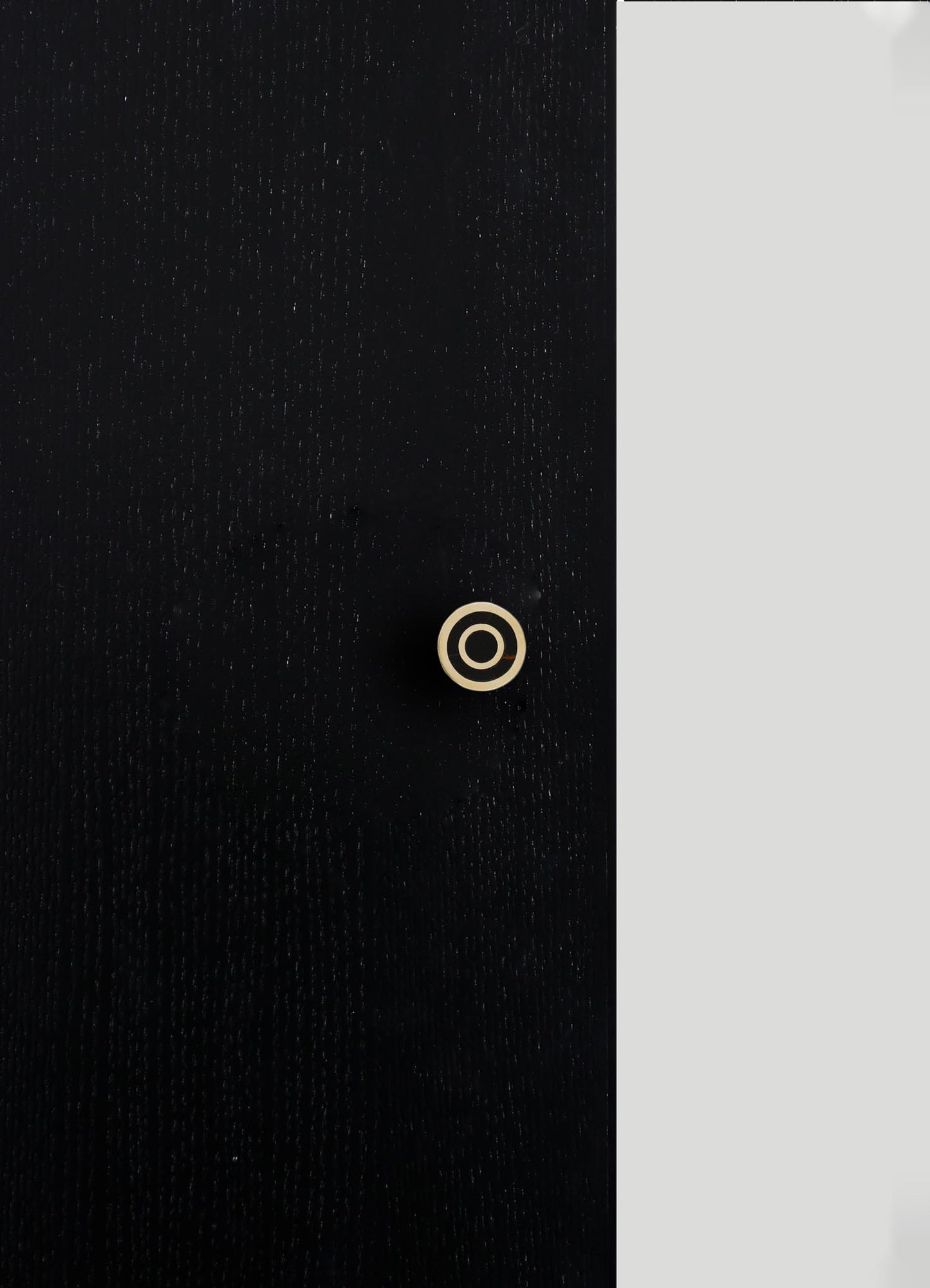 A black fabric with a subtle textured pattern and a small, concentric circular detail in beige. The fabric appears to have a smooth finish with fine stitching or weave.