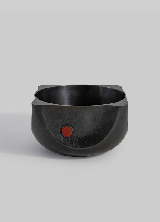 A black hammered metal bowl with a rounded shape and smooth interior, featuring a small red circular accent on the exterior surface.