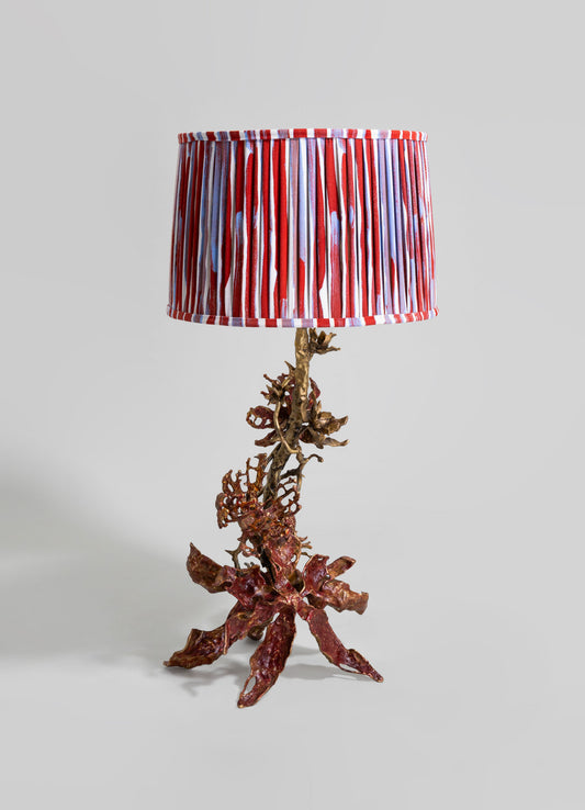 Table lamp with a base resembling intertwined coral branches made of metallic material, finished in a bronze tone. The lampshade features a striped pattern with red, white, and blue colors.