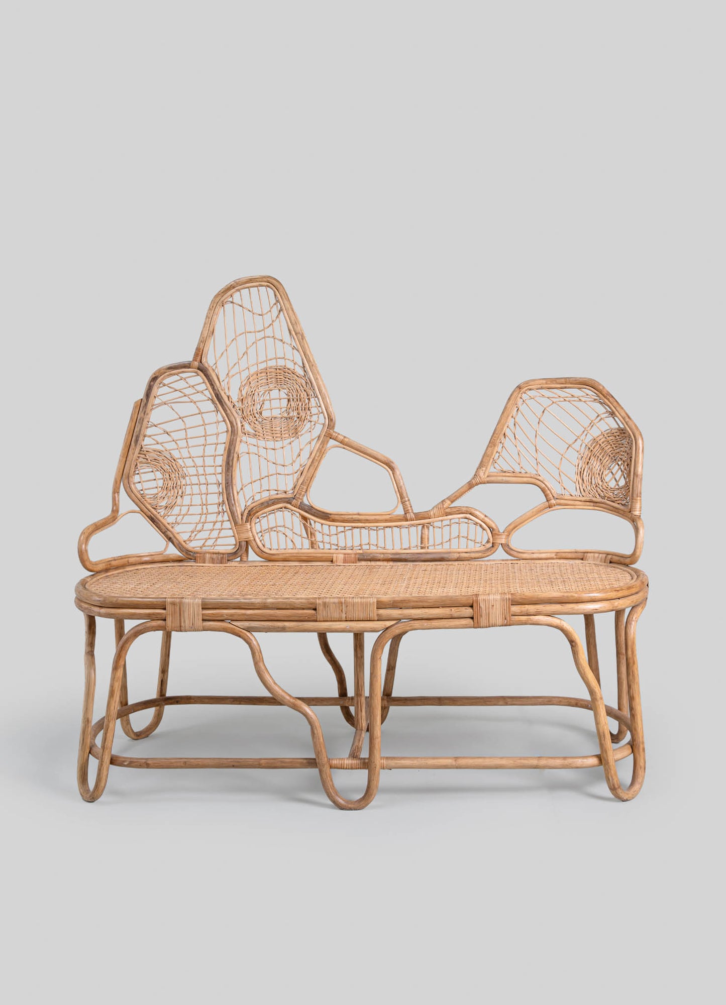 Wicker daybed with an intricate geometric and floral pattern, featuring a natural rattan finish and woven seat, set against a plain light gray background.