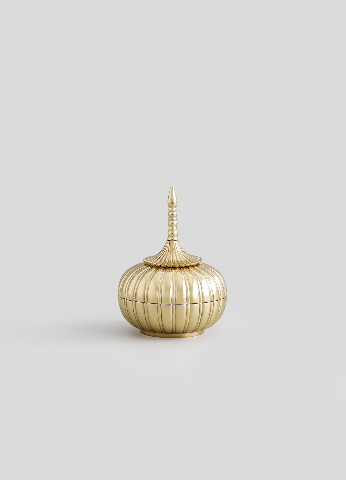 Gold-toned decorative box with a ribbed, rounded body and a tall, pointed lid featuring stacked rings, crafted from metal with a polished finish.