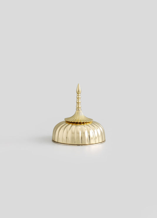 A decorative object resembling a brass or gold-toned container with a scalloped, dome-shaped body, a fluted finial, and a pointed top. The surface features a polished, reflective finish with intricate detailing, giving it an elegant and vintage style.