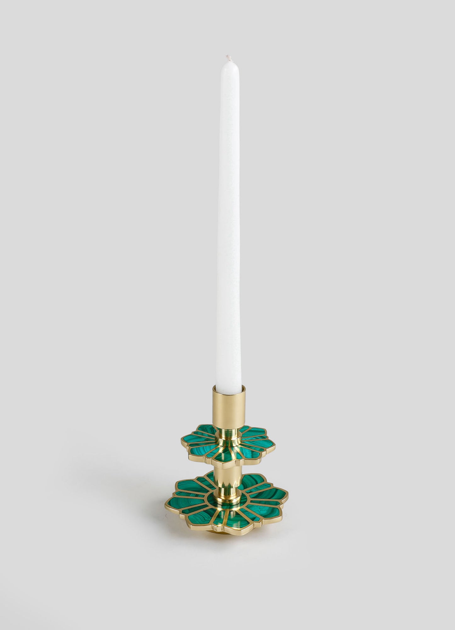 A decorative candle holder made of metal with a gold finish, featuring two layered floral motifs in green with gold accents, designed to hold a taper candle.