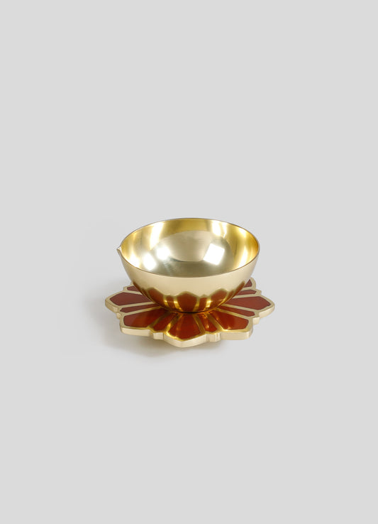 A decorative bowl with a polished gold interior and a floral-shaped base with red and gold enamel accents, made of metal.