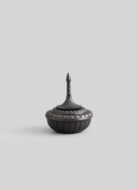 Decorative metal container with a dark, matte finish featuring a ribbed, rounded base and a fluted lid with a finial handle, inspired by traditional Asian design.