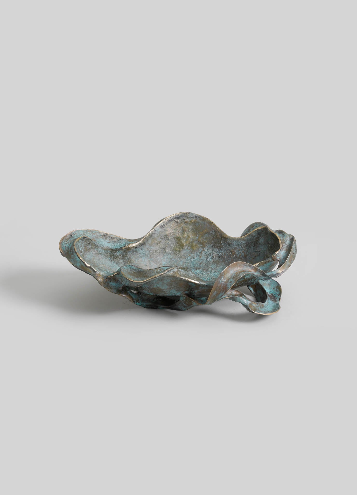 A metal bowl with an organic, irregular shape featuring a textured, aged finish in shades of blue and gray, with wavy, flowing edges and a rustic, handcrafted style.