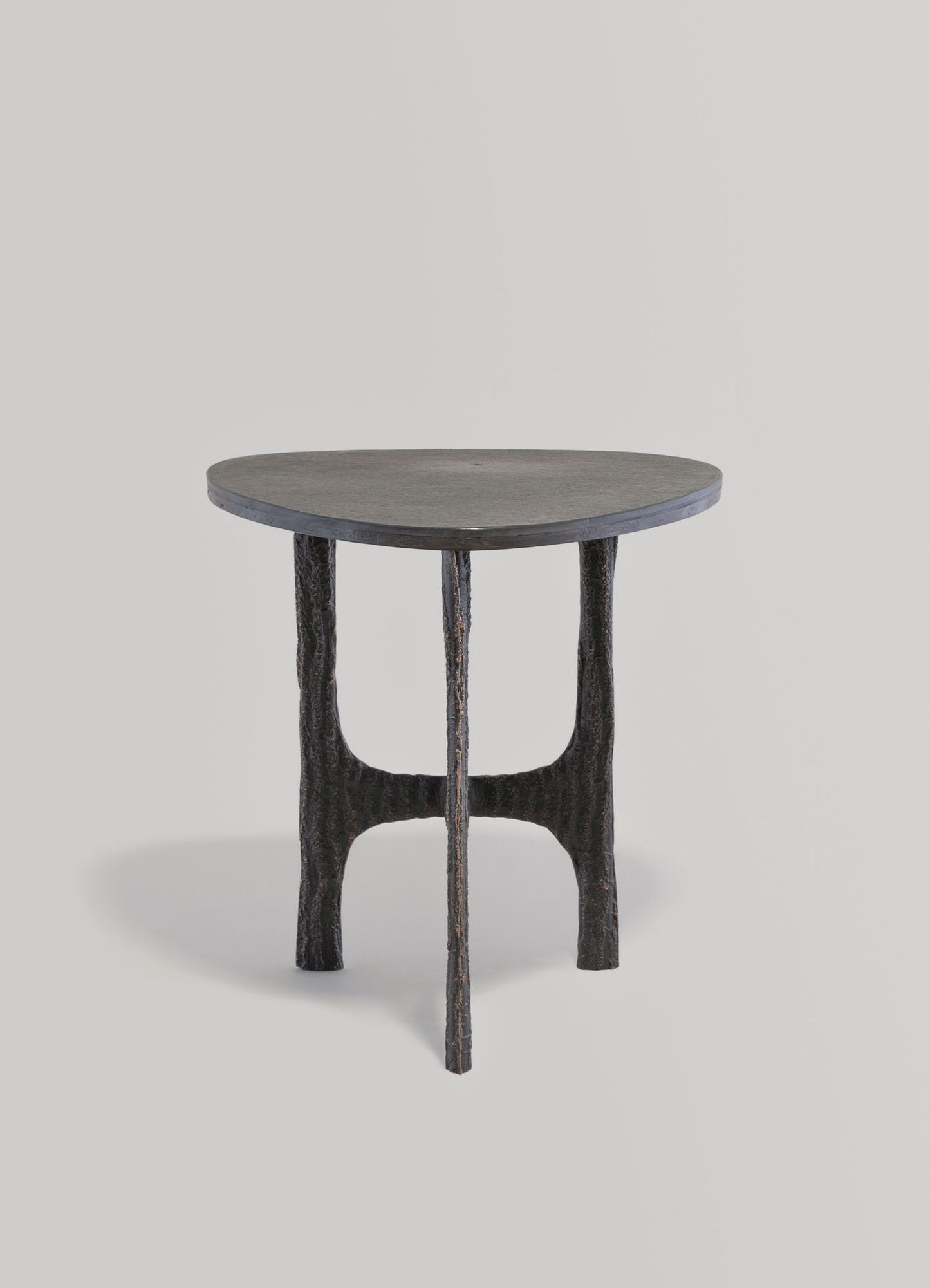 Round wooden side table with a dark, textured finish and curved, sculptural legs. The design combines organic shapes with a matte surface, suitable for contemporary or rustic interior styles.