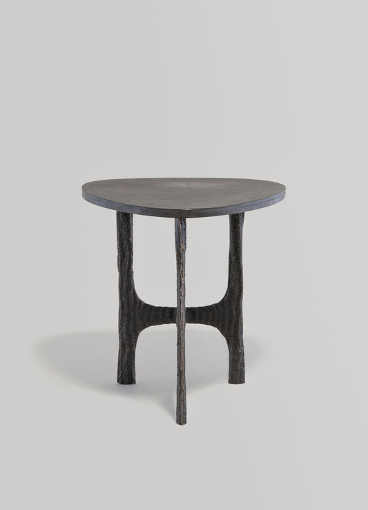 Round wooden side table with a dark, textured finish and curved, sculptural legs. The design combines organic shapes with a matte surface, suitable for contemporary or rustic interior styles.