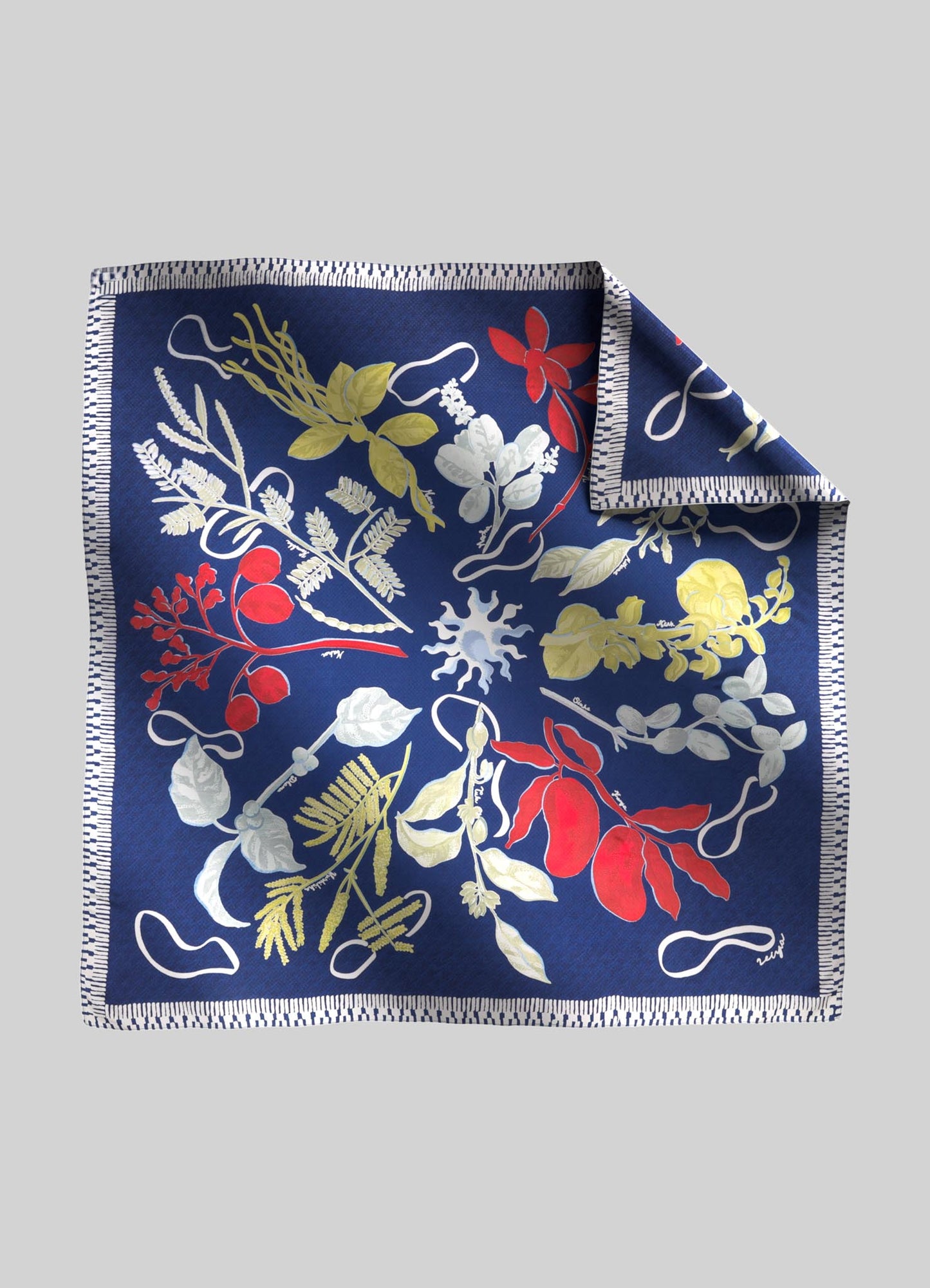 A silk scarf featuring a botanical print with red, white, and yellow floral motifs on a deep blue background, bordered with a stitched trim.