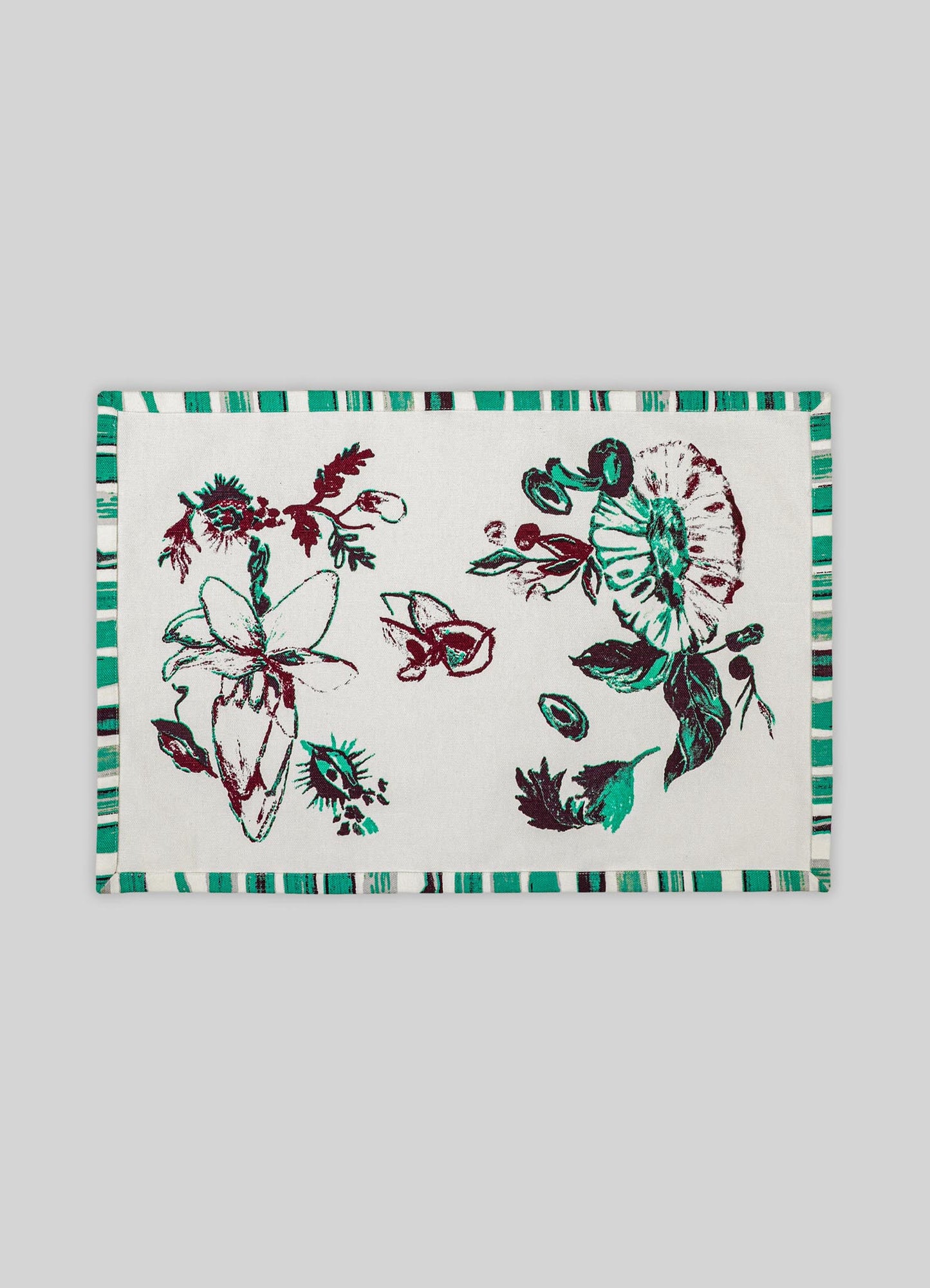 A rectangular fabric placemat featuring a botanical print with abstract floral motifs in shades of teal, maroon, and black on a white background, bordered by a striped pattern in coordinating colors.