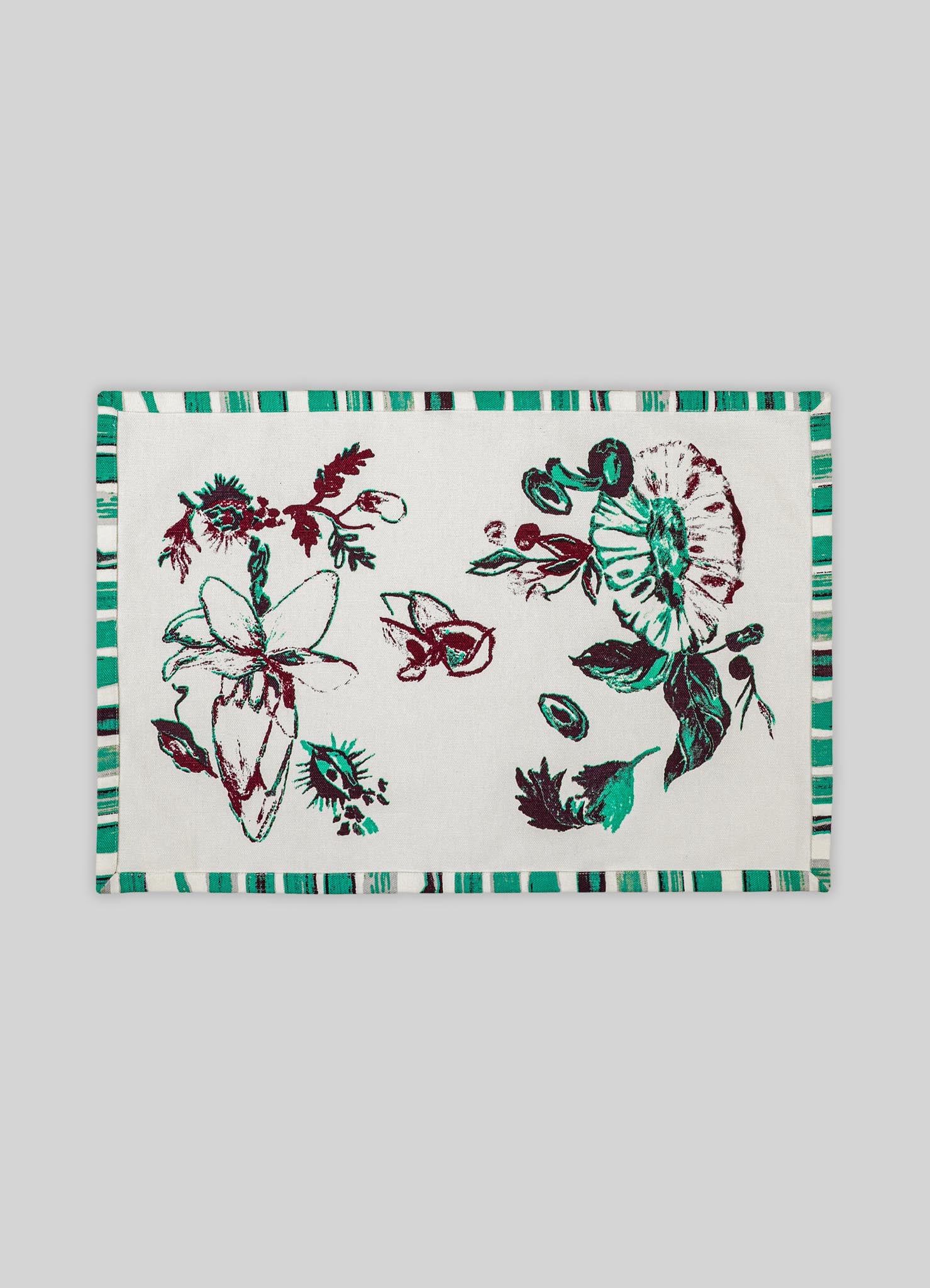 A rectangular fabric placemat featuring a botanical print with abstract floral motifs in shades of teal, maroon, and black on a white background, bordered by a striped pattern in coordinating colors.