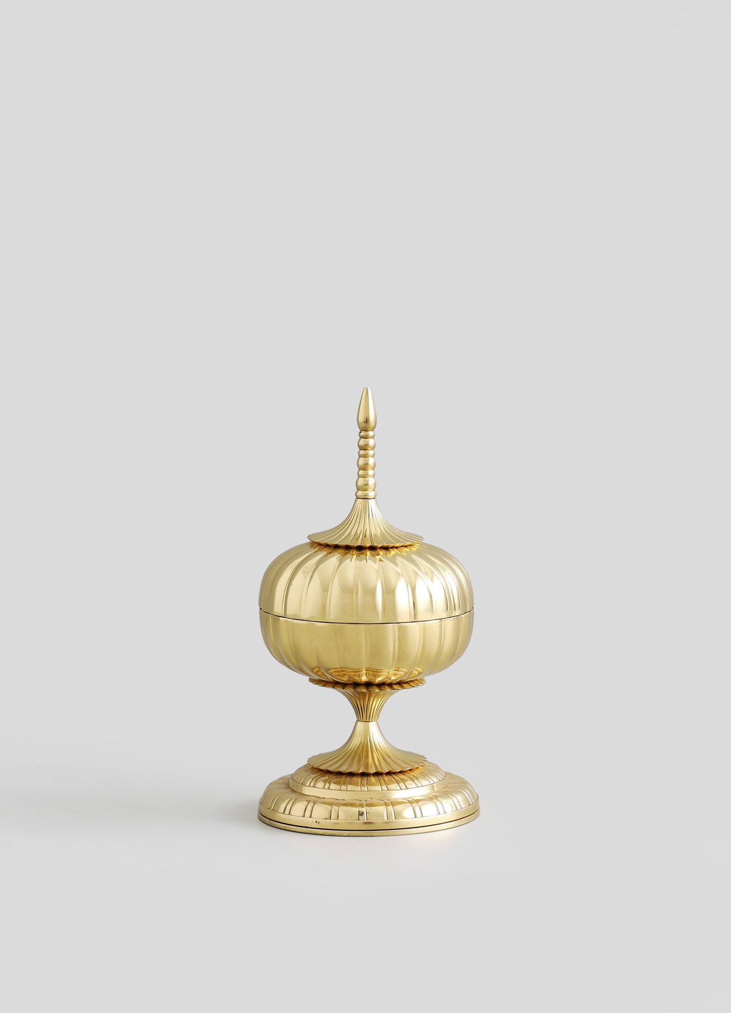 A gold-plated decorative container with a tiered, rounded body and a pointed finial on top, featuring ornate, ribbed details and a pedestal base. The design is elegant and vintage-inspired, with a polished finish.
